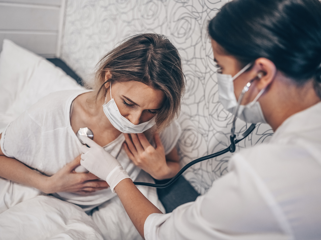 Doctora oscultando a una paciente con dificultad para respirar, uno de los síntomas de la COVID19