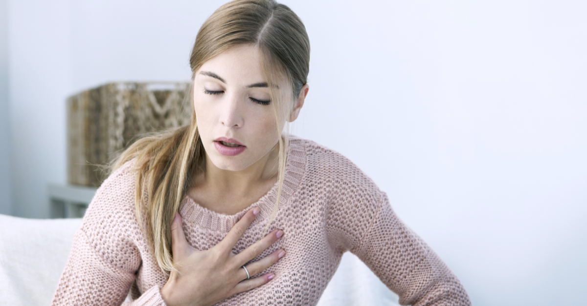 mujer con la mano en el pecho y dolor torácico