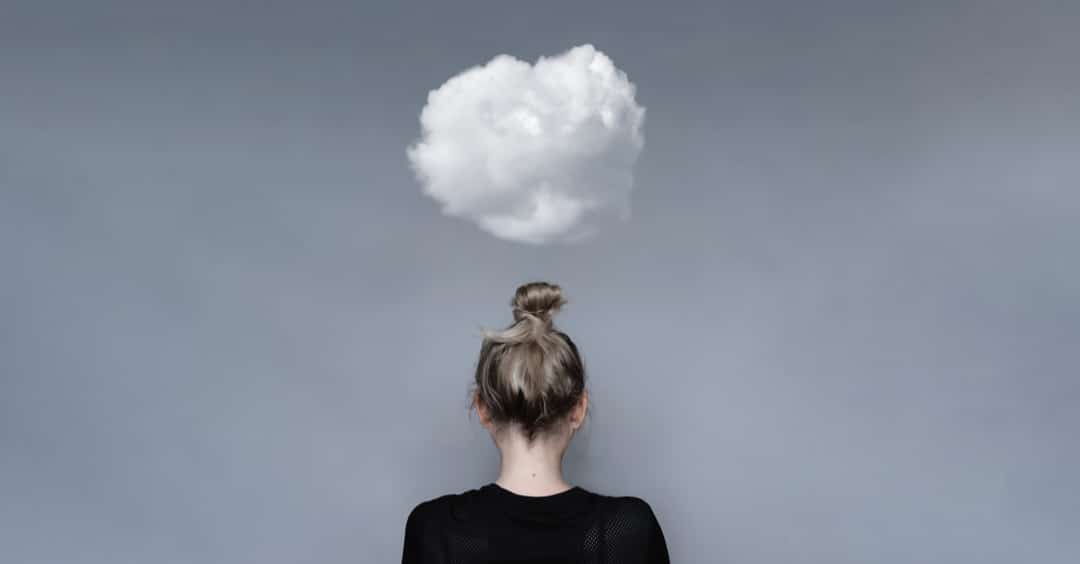 Mujer de espaldas con nubes encima de su cabeza. Concepto de salud mental, depresión, soledad.