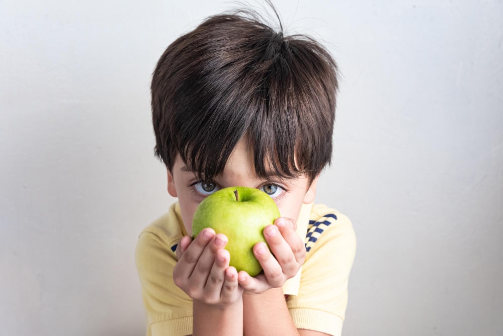 chico comiendo manzana verde - Los niños con sobrepeso en España alcanzan cifras alarmantes, estamos ante la 'epidemia del siglo XXI' según declara la OMS